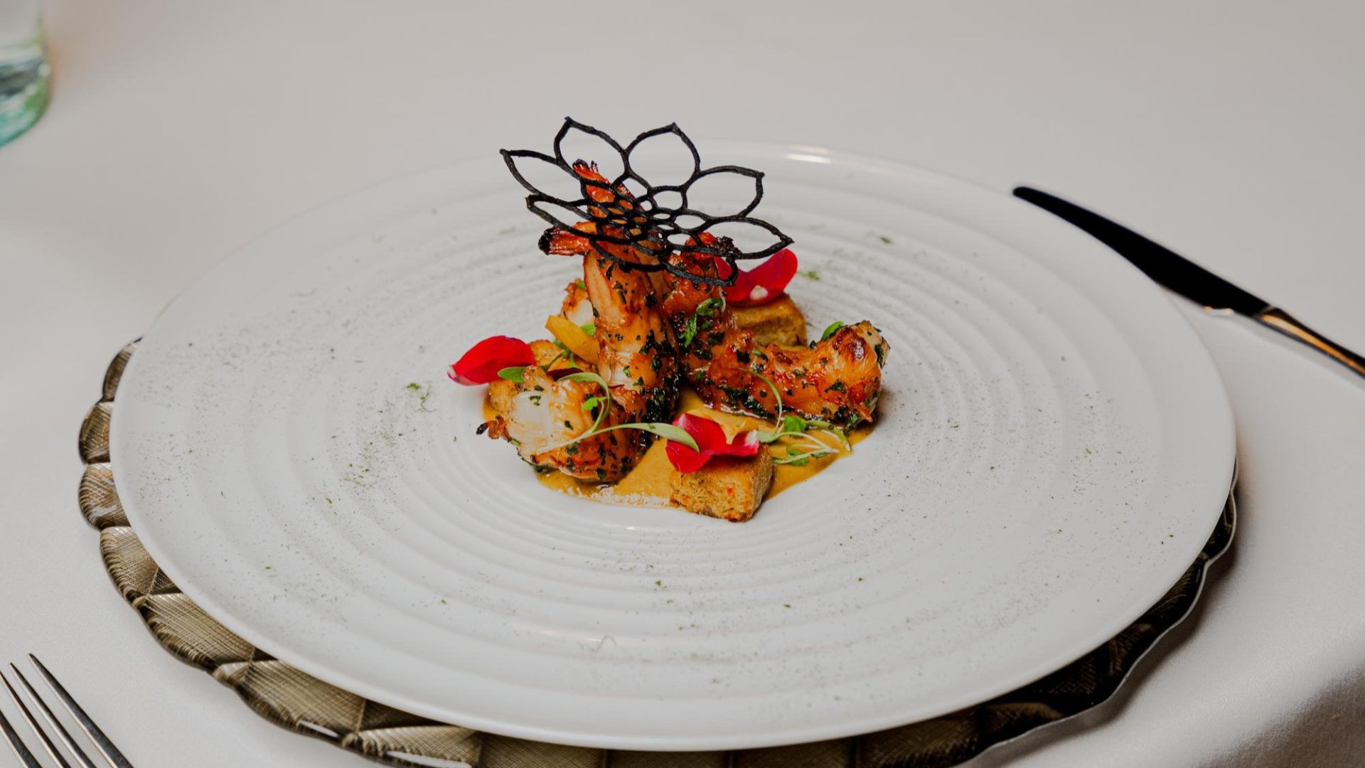  Primer plano de un plato blanco con una comida de alta gastronomía a base de langostinos.