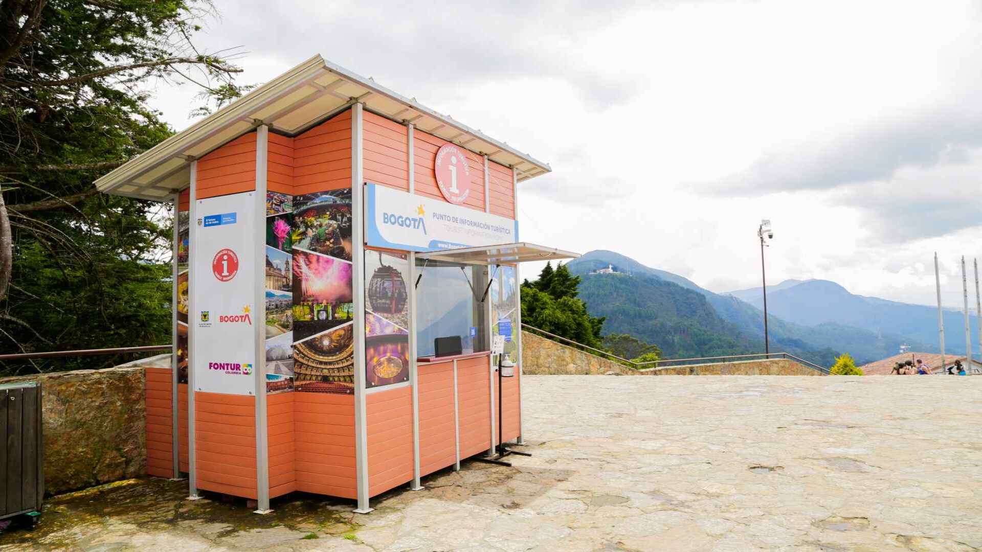 Un pintoresco quiosco de información turística de Bogotá al aire libre con montañas de fondo.