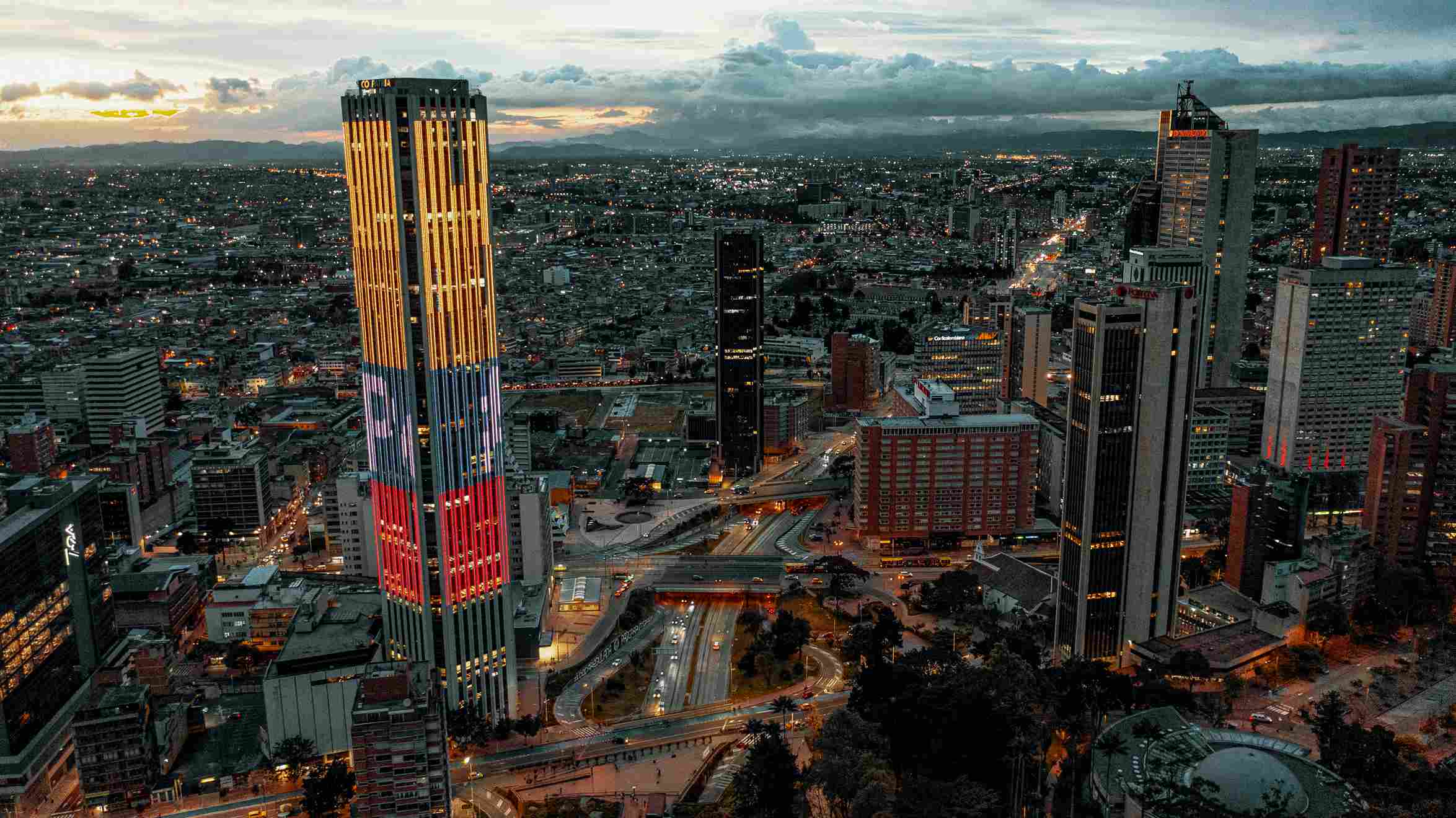 Aerial view of Bogotá, showing the huge Simón Bolívar Park, with buildings and mountains in the background on a clear day.