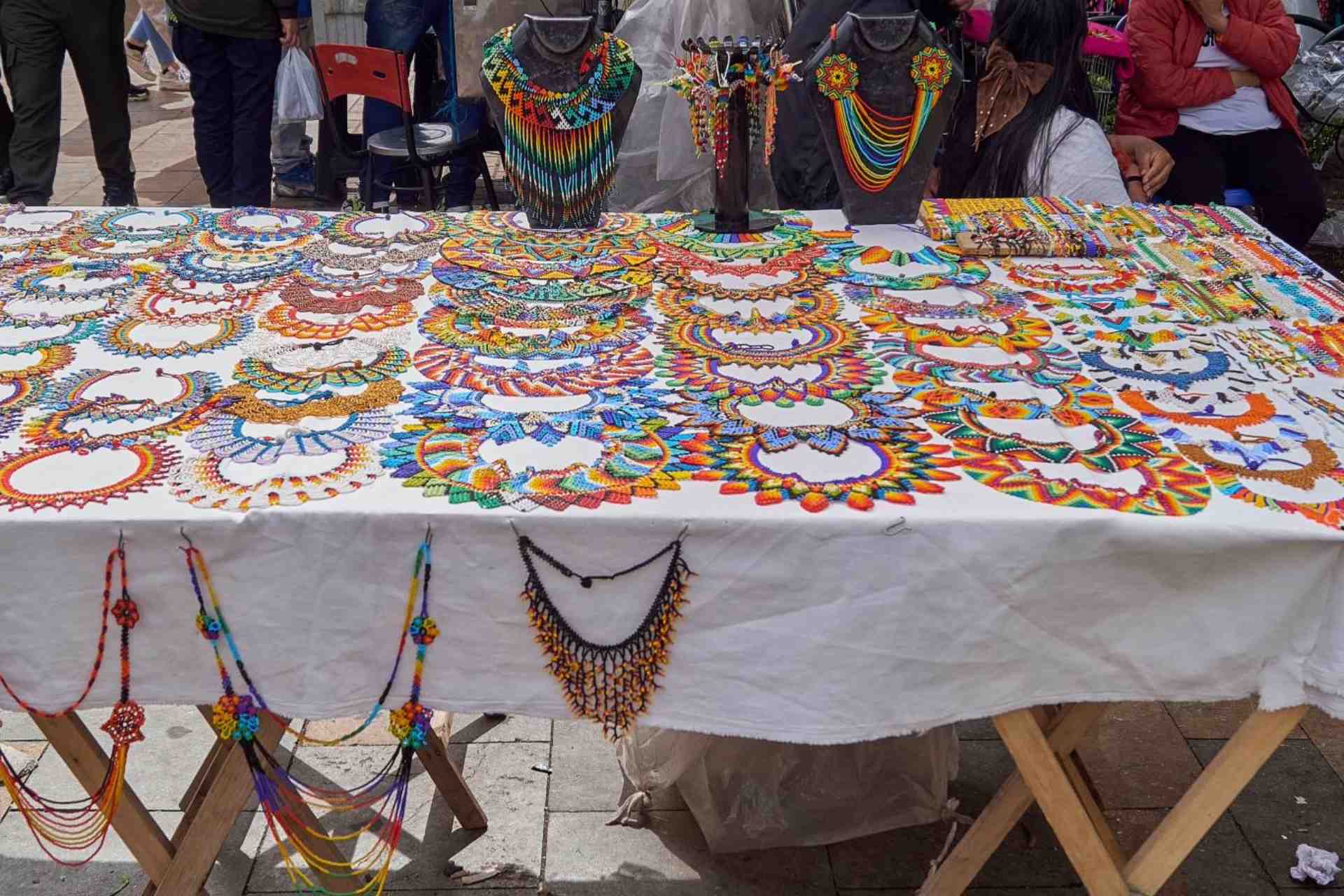 Mesa en la calle con artesanías coloridas colombianas como aretes y collares.