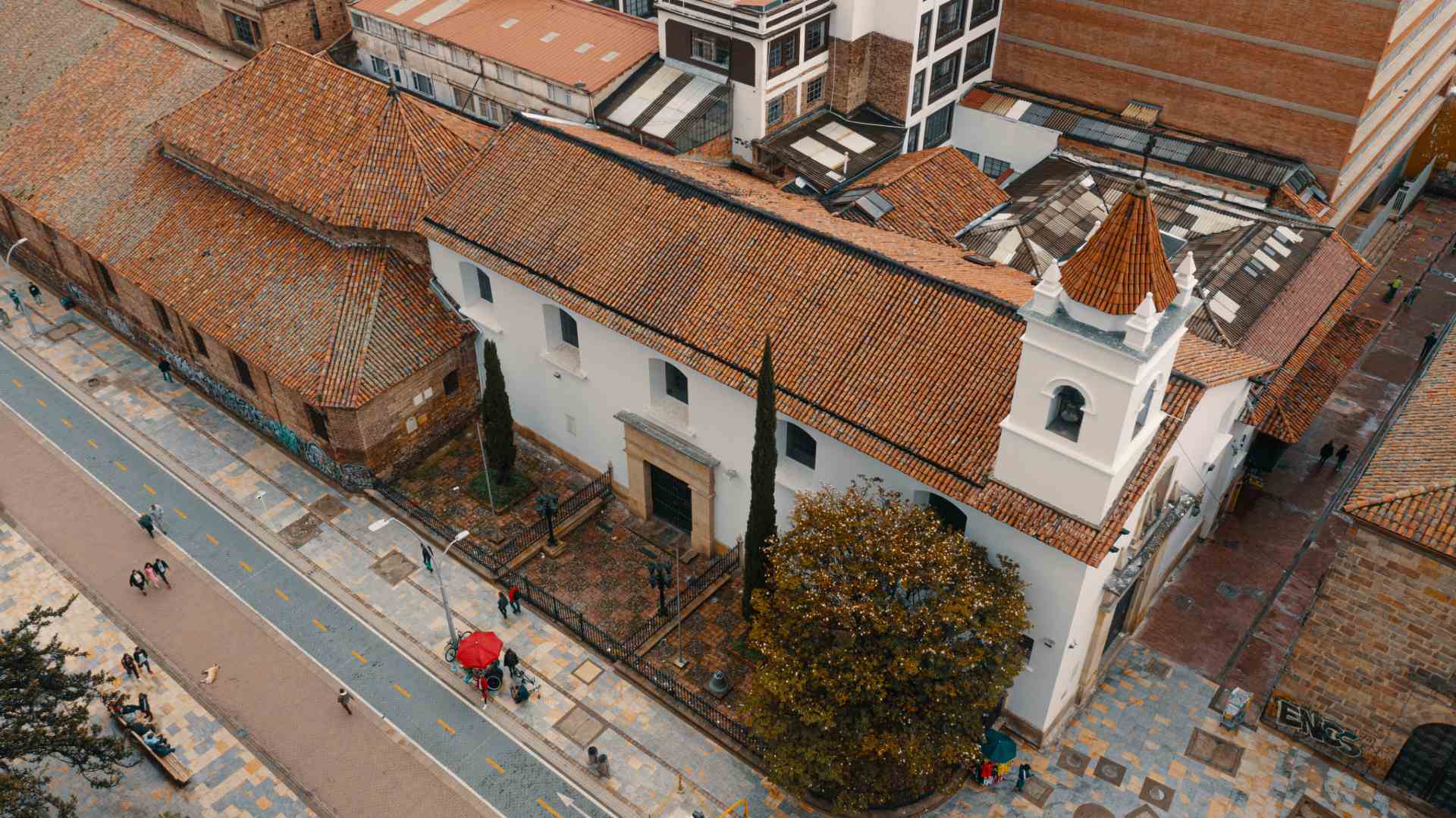 Iglesia de La Veracruz el techo desde arriba tomado con dron, su fachada adronada con dos pinos y un árbol. Se ve la carrera séptima.