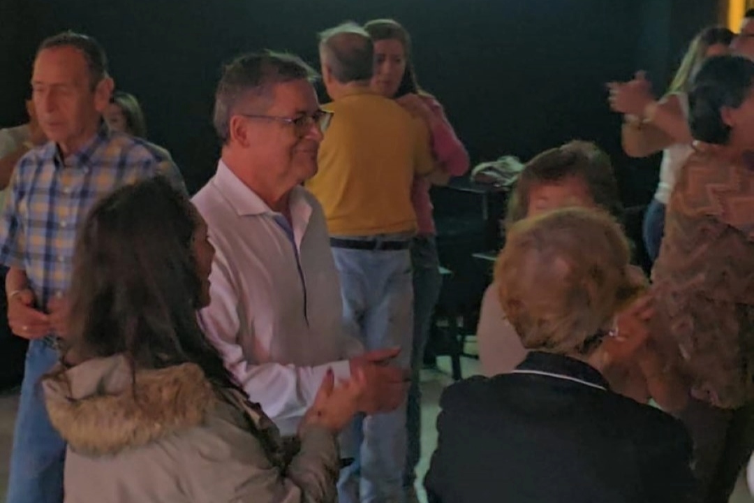 Grupo de personas adultos mayores bailando y sonriendo.