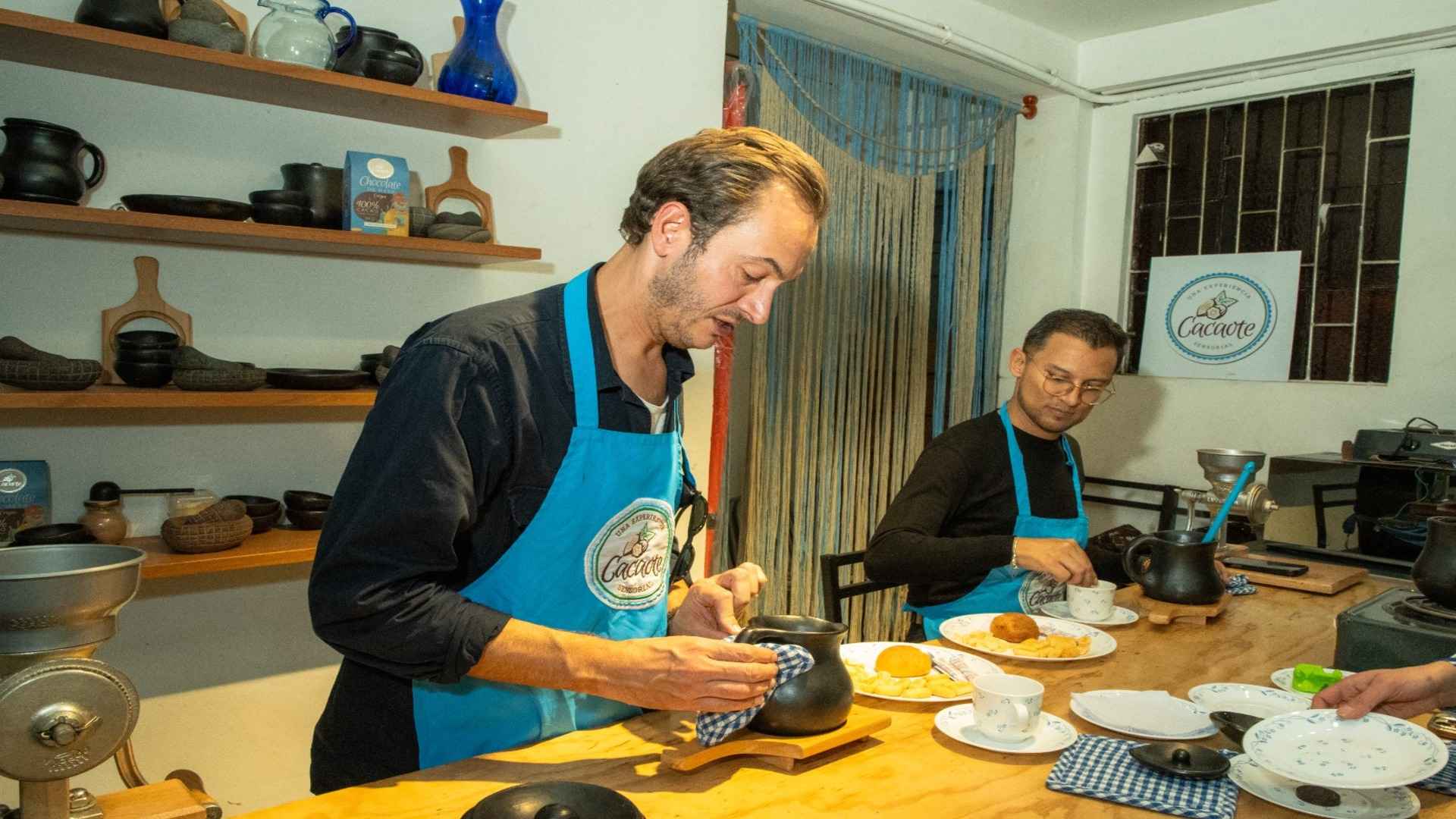 Un músico con delantal azul manipulated una jarra de barro en un taller de cacao y chocolate tradicional.