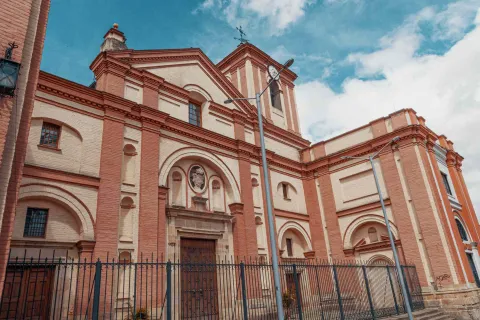 Iglesia San Ignacio fachada completa de lado con un poste eléctrico al frente y el cielo azul con algunas nubes.