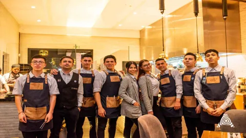 Un grupo de jóvenes y amables miembros del personal del restaurante Tierra posando orgullosamente en su lugar de trabajo.