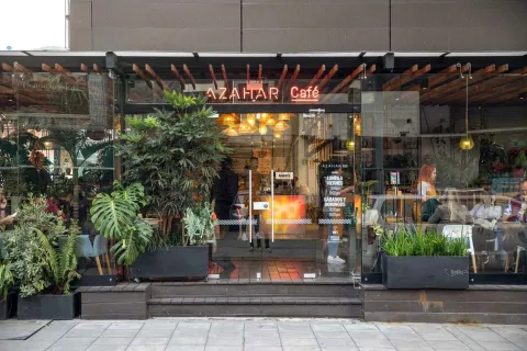 Fachada de Azahar Café El Nogal, un espacio moderno con ventanales, plantas y un ambiente acogedor en la ciudad.