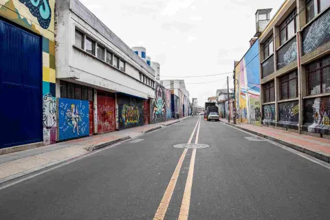 Calle vacía en la que hay paredes a lado y lado pintadas con graffitis de muchos colores.