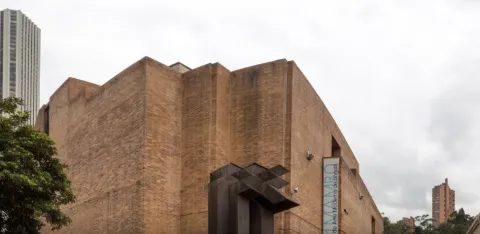Fachada de gran edificio en ladrillo donde sobresale un aviso con una leyenda en letras azules que dice: “MAMBO”.
