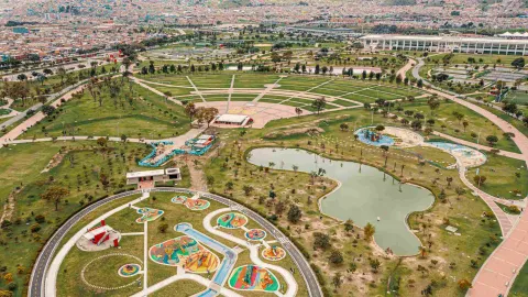 Wide shot from above of a huge park with sports fields, large green areas, and a large lake.