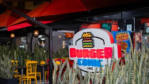 FOTO 1: Un letrero luminoso de "BURGER COMIC INC" con una hamburguesa pixelada brilla por la noche en la entrada del restaurante.