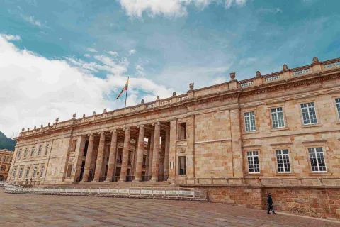 Fachada del Capitolio Nacional en piedra. Se observan algunas ventanas y la bandera de Colombia izada en lo alto.