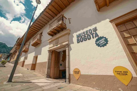 Facade of the entrance to the Bogotá Museum, where seven wooden balconies stand out and a couple of legends that say: 'Bogotá Museum' and 'Free entry'.