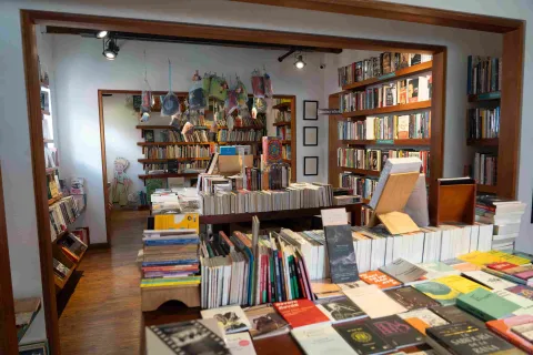 Interior of a bookstore with wooden shelves full of books, display tables, and a children's section in the back decorated with illustrations.