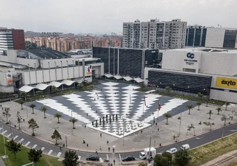 Vista aérea del centro comercial Gran Estación en Bogotá, con una amplia plaza central de diseño geométrico rodeada de edificios y vías urbanas.