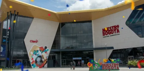 Fachada moderna del centro comercial Nuestro Bogotá, con amplios ventanales, diseño contemporáneo y decoración colorida en la entrada.