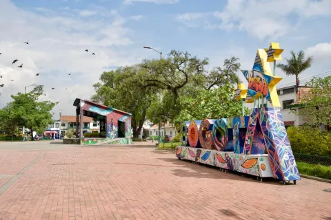 Bosa's main square, featuring a sign with colorful letters spelling out the word Bogotá. It's a cultural space with trees, in an open, urban setting.