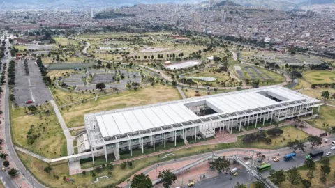 Aerial view of the El Tunal Happiness Center (CEFE) and its urban surroundings in southern Bogotá. The image shows ample green spaces, pedestrian walkways, sports facilities, and recreational areas integrated with the complex's modern infrastructure, surrounded by the city's extensive urban fabric and the mountains in the background.
