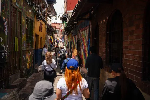 Visitors walking down a cobblestone alley in La Candelaria surrounded by colorful colonial facades and street art murals.