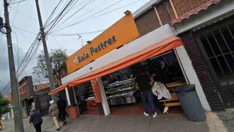 Porción de pastel de tres capas de chocolate y crema exhibido en primer plano dentro de una vitrina refrigerada. 
