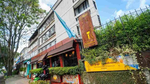 Foto 7: Fachada exterior del restaurante con letreros de madera, plantas, banderas y toldos sobre la acera.