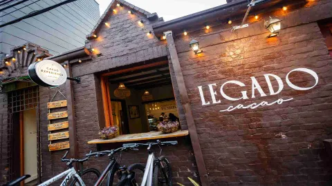 Fachada de ladrillo de Legado Cacao de día con bicicletas parqueadas y letrero en la pared exterior. 