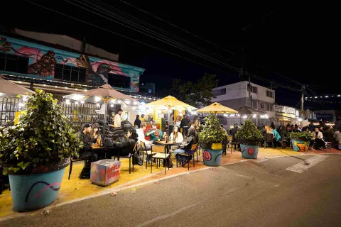 Night view of San Felipe in Bogotá, featuring outdoor restaurant tables under warm lighting beside street art murals.