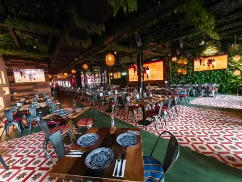 Amplio y colorido interior de Cantina La 15, con decoración mexicana, mesas dispuestas para los comensales y abundante vegetación.