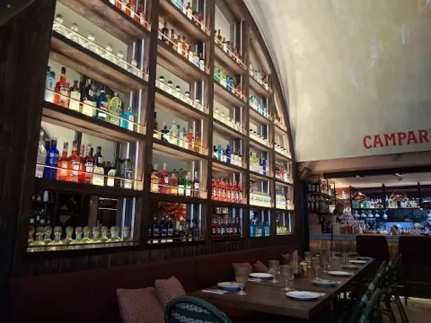 Interior de Via Del Cuore, con barra de coctelería y estanterías de bebidas que complementan su ambiente italiano.