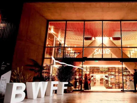 Fachada iluminada del Bogotá Wine & Food Festival, con grandes letras blancas y acceso a un espacio gastronómico.