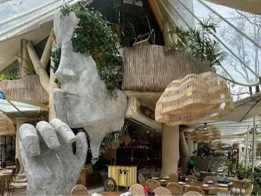 Interior de Malaflor con decoración inspirada en la naturaleza, grandes esculturas, vegetación abundante, mobiliario artesanal y un ambiente tropical y creativo.