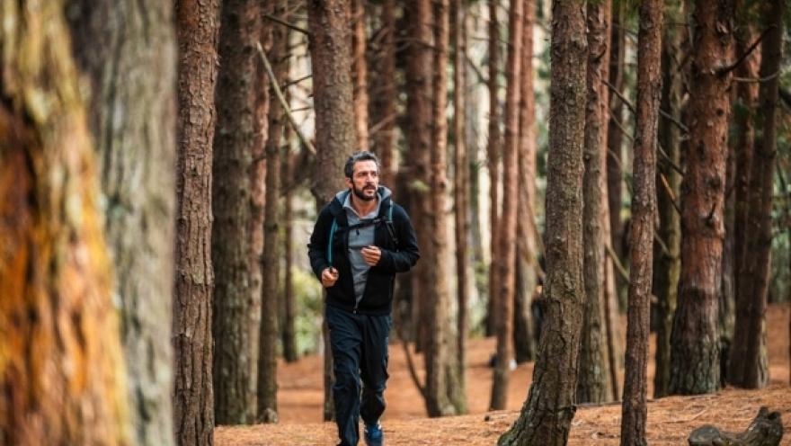 Sendero Quebrada La Vieja hombre en sudadera trota alrededor de los árboles.