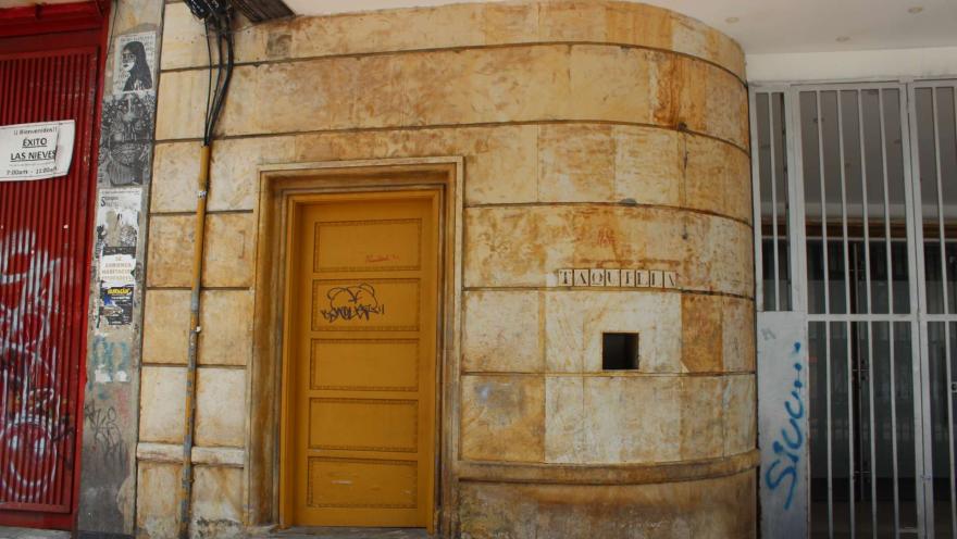 Auditorio Mayor con puerta amarilla en la fachada con algunos grafitis y un letrero que dice taquilla.