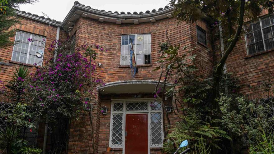 Chapinero primer plano fachada casa estilo inglés en ladrillo, rodeada de árboles y plantas altas como enredaderas.