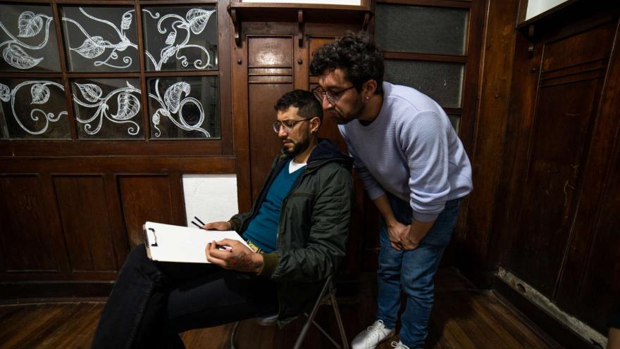Chucuy Club con un par de hombres jóvenes observan el dibujo que hizo uno de ellos. 