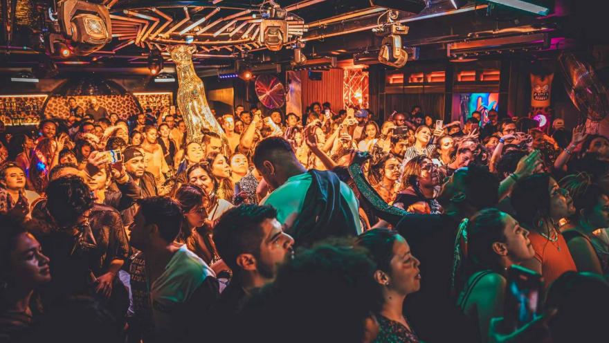 Disco Jaguar salón atestado con decenas de personas que bailan y ríen rodeando una figura de jaguar dorado.