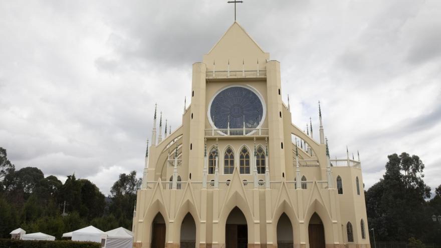  Iglesia Caballeros de la virgen nuestra Señora de Fátima, fachada completa de frente rodeada de árboles y cielo gris con nubes blancas