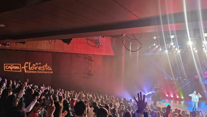 Teatro Cafam interior escenario lleno con público que levanta las manos,  con luces reflectivas y cantante en el escenario.  