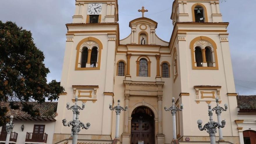 Basílica Menor de San Jacinto en primer plano de fachada vista en contrapicado con dos mujeres y un hombre que camina hacia su puerta. El cielo está gris.