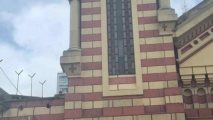 Iglesia de Las Nieves en el exterior la alta torre del reloj y el cielo azul con nubes. La puerta principal de madera se ve abierta pero cerrada con una reja metálica.
