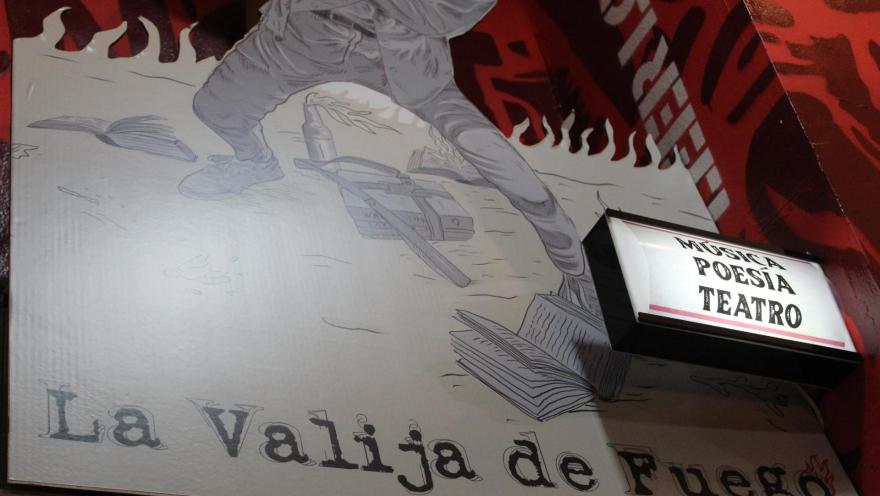 Librería La Valija de Fuego su afiche en primer plano con el nombre de la librería con un aviso con luz en el que se lee Música, Poesía y Teatro.