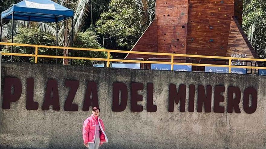 Mujer adulta piel castaño y chaqueta rosa delante del letrero Plaza del Minero. 