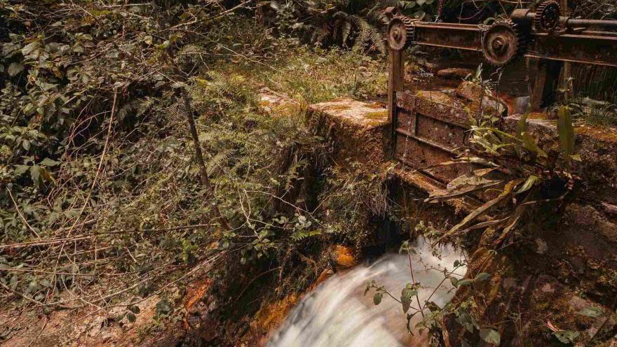 Sendero San Francisco - Vicachá profusa caída de agua sobre puente metálico rodeado de vegetación.