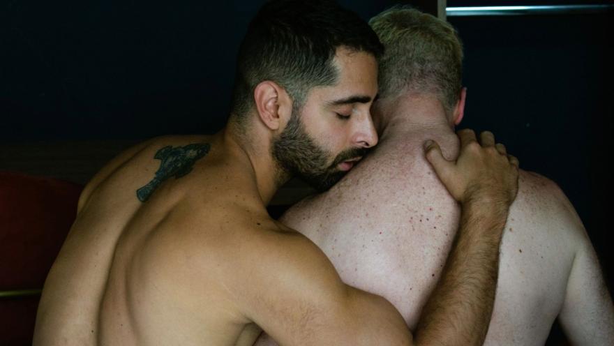  Barraca Teatro con dos hombres jóvenes con el torso desnudo y de espaldas abrazados.