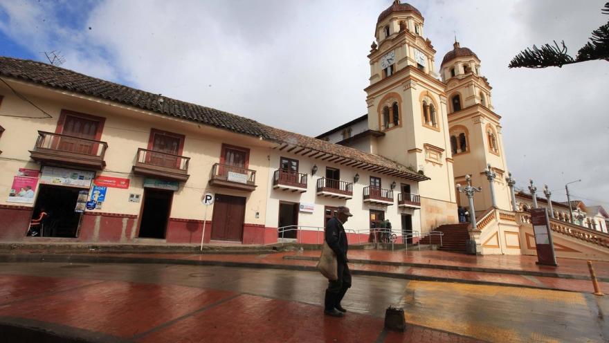  Basílica Menor San Jacinto - Guasca vista lateral con casas aledañas. Al frente camina por los andenes un hombre adulto mayor.