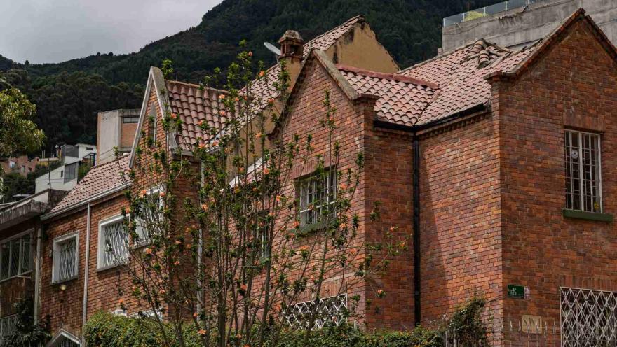 Chapinero plano general de fachadas casas estilo inglés en ladrillo, techos con teja de barro, algunas flores al frente y al fondo de los techos los cerros orientales.