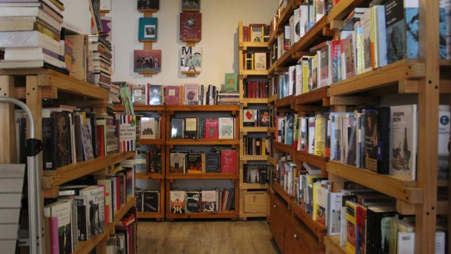 Garabato Libros, pasillol rodeado a los lados y al frente con estanterías de madera de 4 y 5 niveles repletas de libros. 