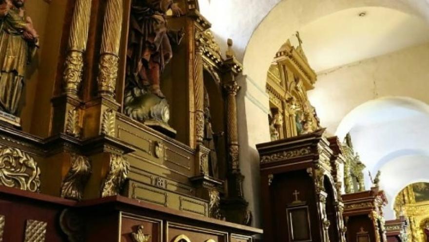 Iglesia de la Candelaria colonial en el interior con retablos en una pared decorada con esculturas religiosas y sus columnas en forma de arcos.