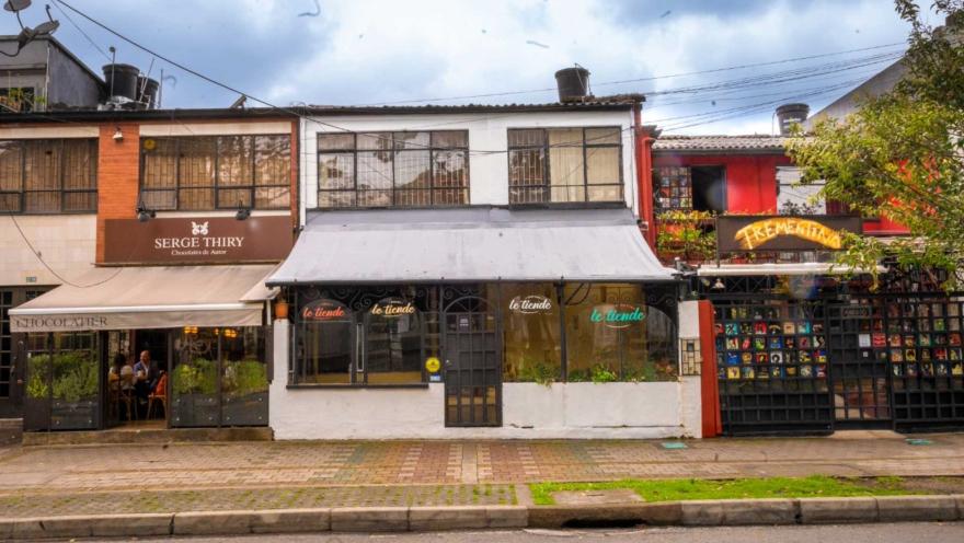 Park Way con fachada de frente tres restaurantes Serge Thiry, Le Tiende y Trementina en casas de dos pisos. Al fondo de uno de ellos se ven personas conversando.