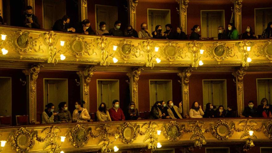 Teatro Colónr with audience members seated in two balconies, some of them wearing face masks.