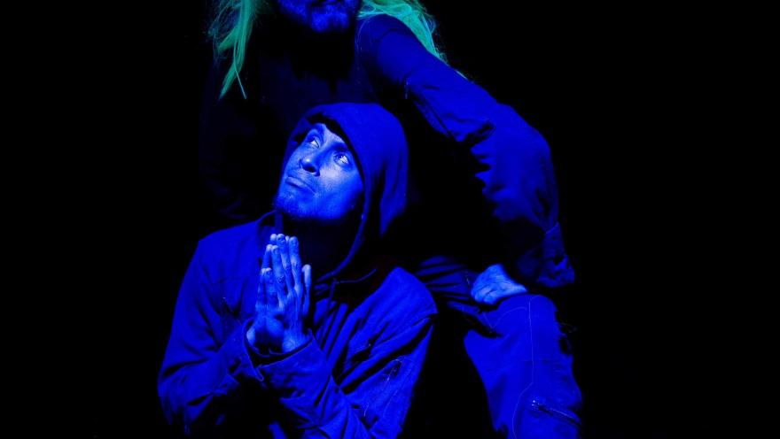  Barraca Teatro con actores en escena arrodillados miran de frente. Uno tiena una peluca amarilla.